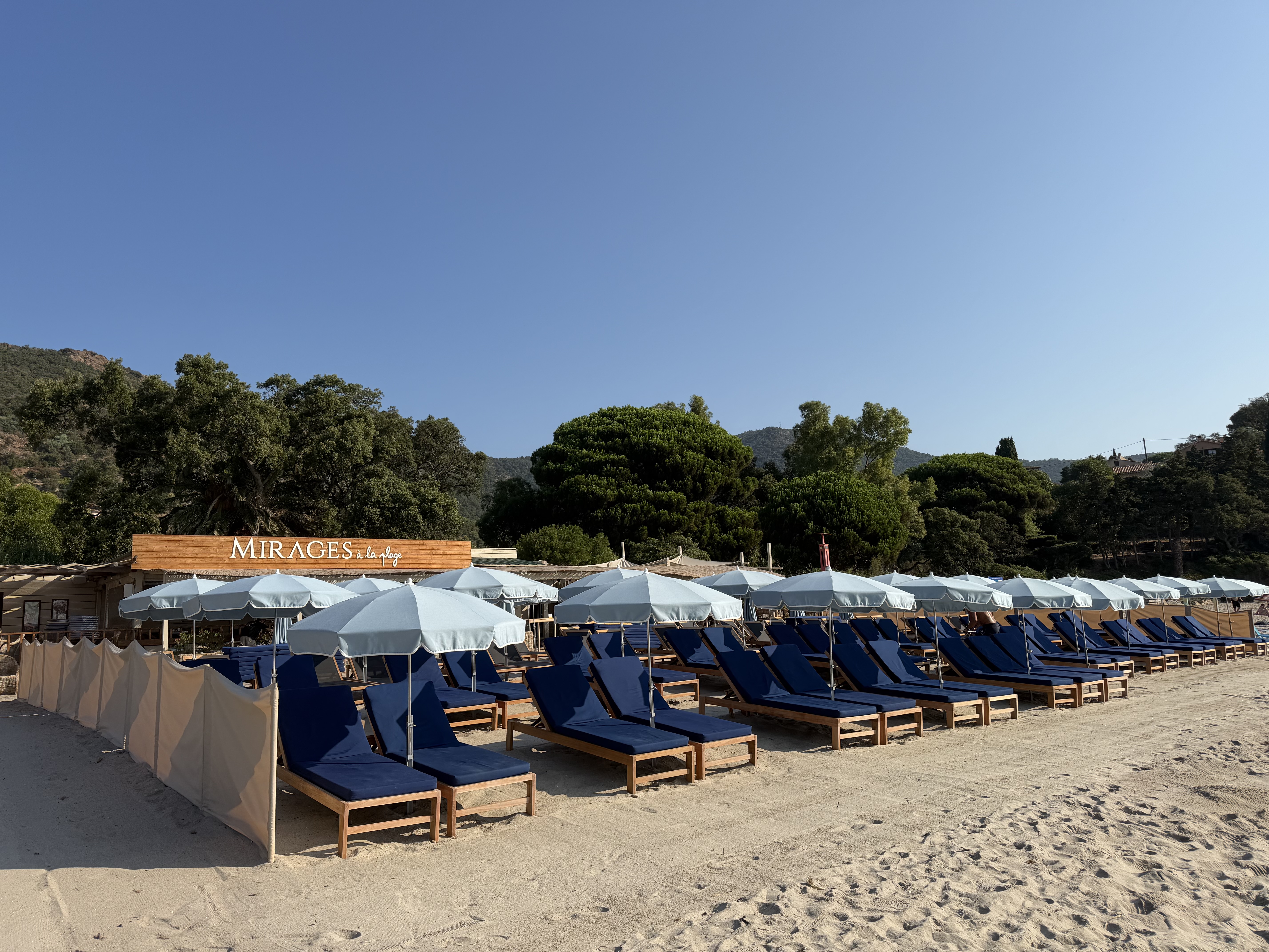 Enseigne Mirages à la plage et rangées de bains de soleil bleus