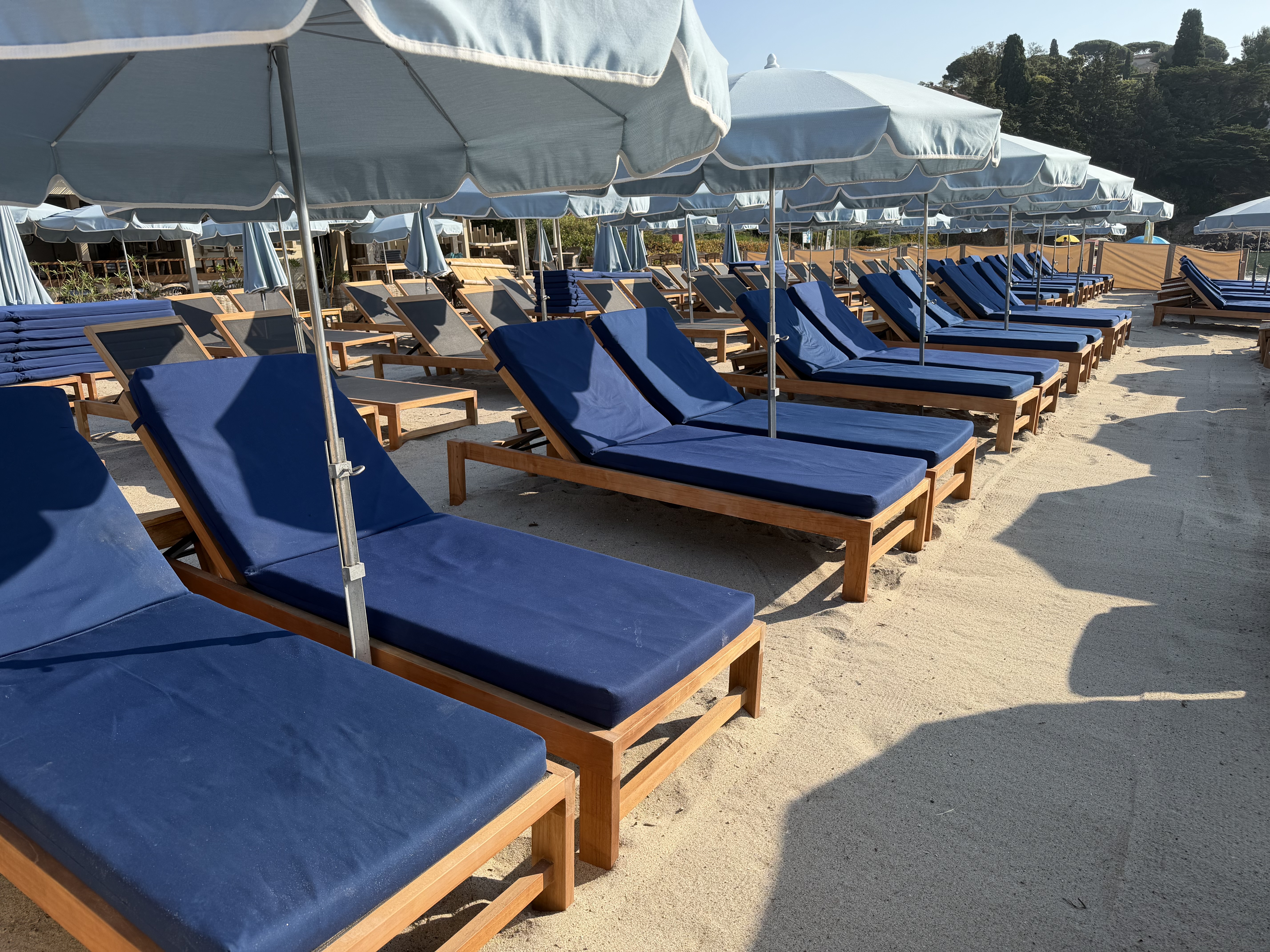 Bains de soleil en teck sous les parasols bleu clair sur le sable